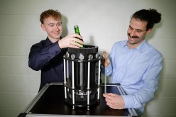 Eine kleine Flasche hat Platz im ersten Mini-Kühlschrank mit künstlichen Muskeln. Student Nicolas Scherer (l.) und Doktorand Lukas Ehl (r.) forschen im Team der Professoren Stefan Seelecke und Paul Motzki am neuen Kühlsystem.  Foto: Oliver Dietze  Universität des Saarlandes