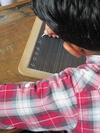 Schreiben auf einer Schiefertafel. Foto: Rüdiger Wulf