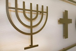 Menorah und Kreuz – Symbole des Judentums und des Christentums; Installation neben anderen religiösen Emblemen im «Raum der Stille» an der Universität Luzern.  Dave Schläpfer  Universität Luzern