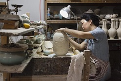 Meisterin Chen Shaoqing in ihrer Werkstatt beim Signieren einer Vase.  Franca Wohlt, 2018