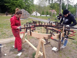 Workshop-Teilnehmerinnen Anne Geyersbach (links) und Schirin Steinhauer kleben die unter Wasserdampf gebogenen Eschenbretter zum Dachkranz zusammen. © HNEE/ Valerie Voggenreiter