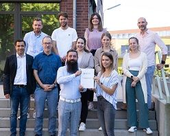 Bei der Übergabe der Projektergebnisse stehen vorn links Ingo Wagner, Geschäftsführer KlimaDiskurs.NRW und rechts neben ihm IST-Studentin Justine Peters von der Projektsteuerungsgruppe.  IST-Hochschule für Management